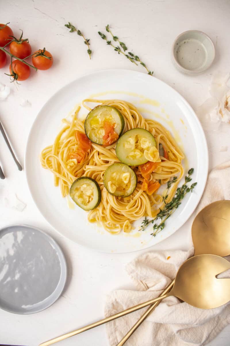 Linguine garlic and oil with zucchini and cherry tomatoes on a plate.