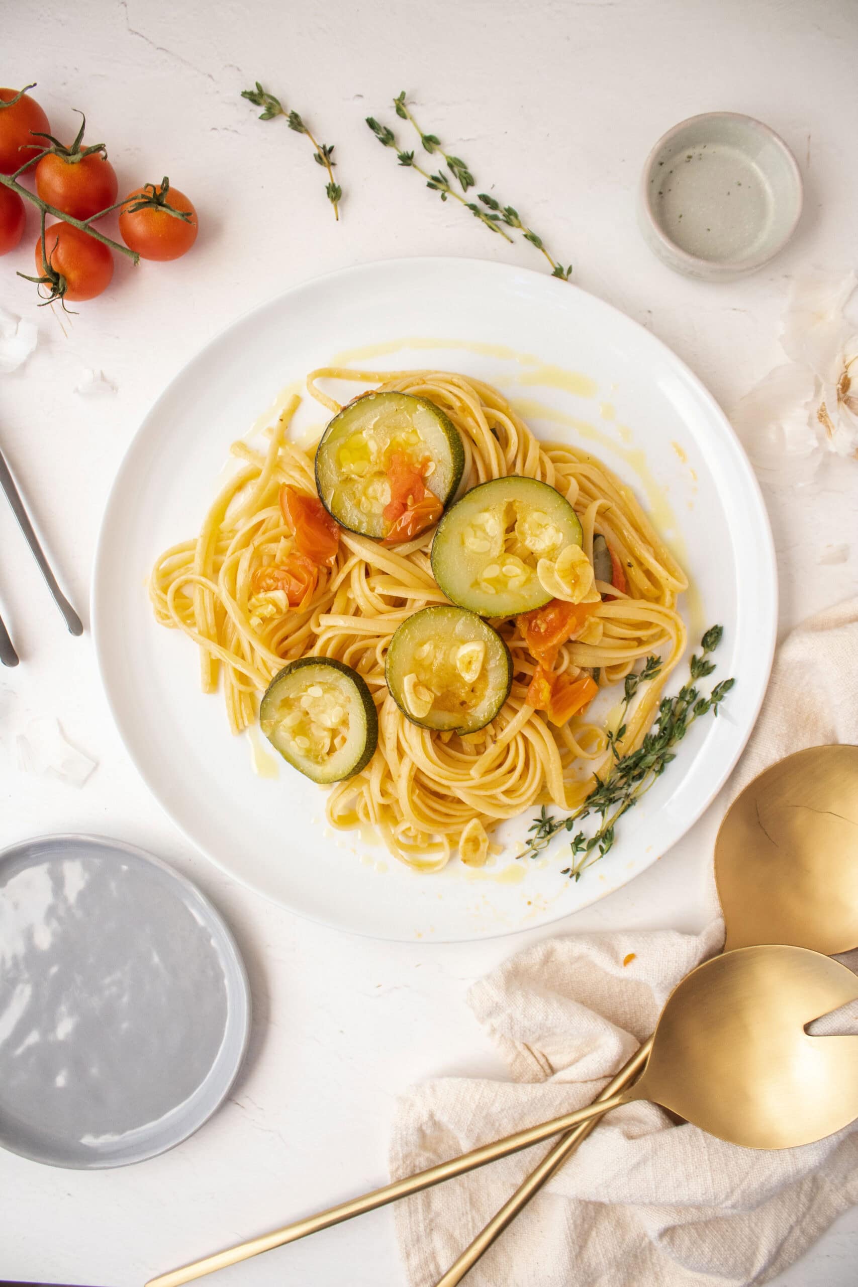 Linguine garlic and oil with zucchini and cherry tomatoes on a plate.