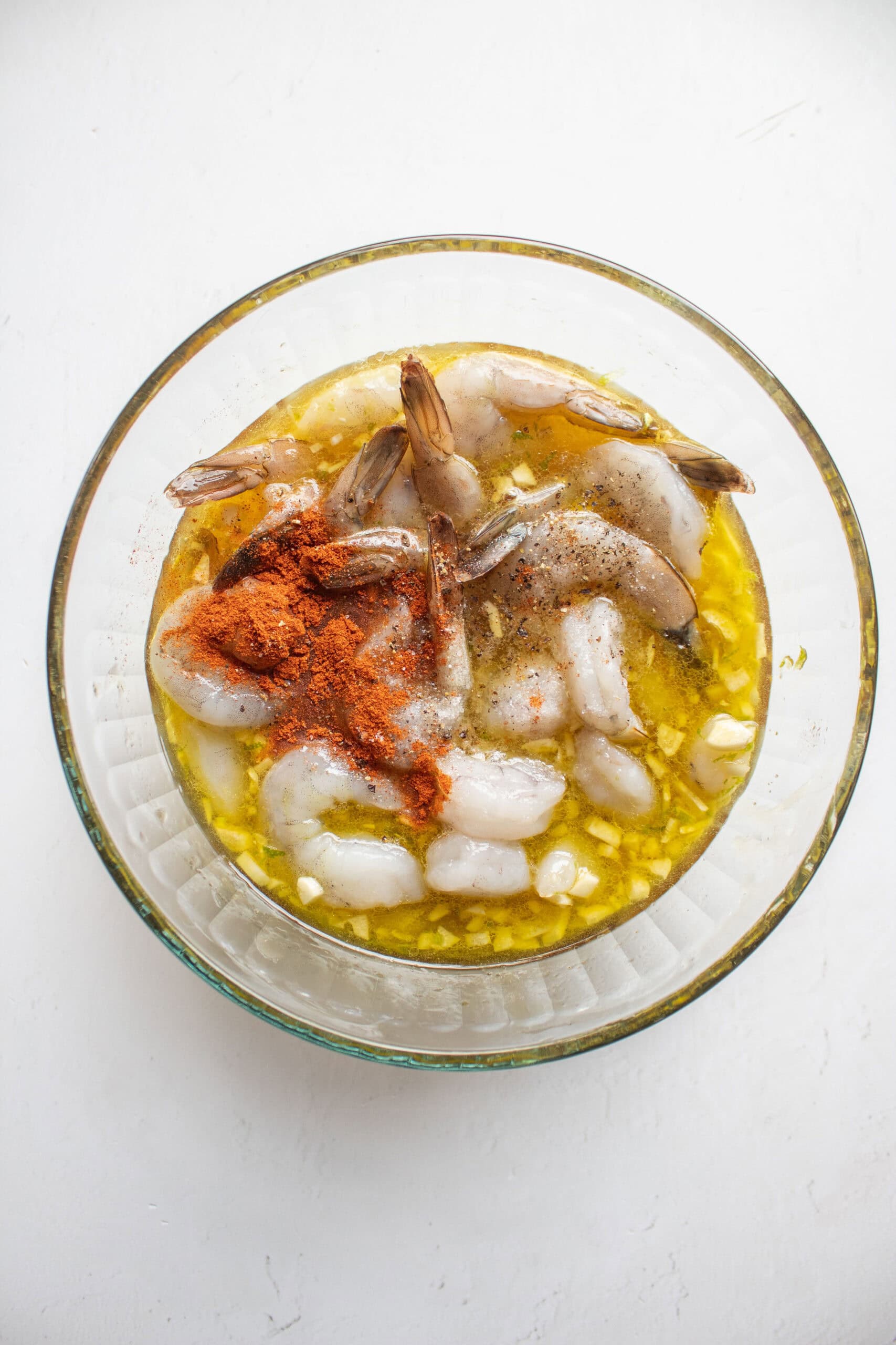 seasoning added to a bowl of shrimp in a honey lime marinade.