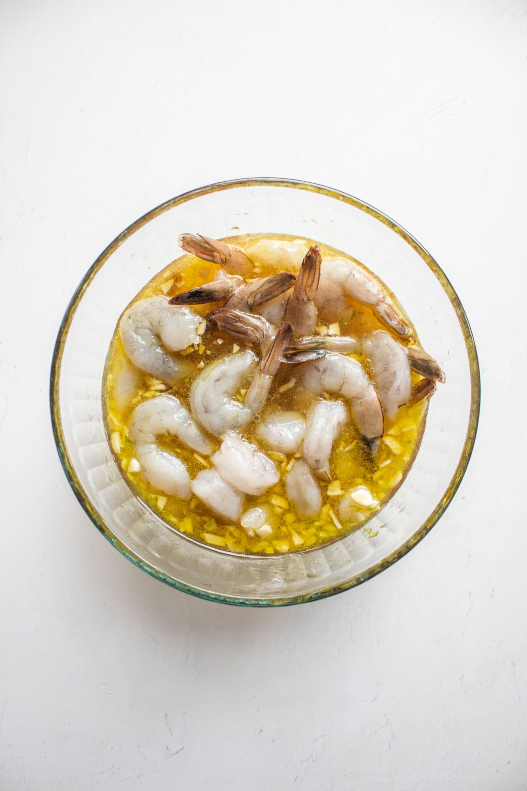 shrimp added to a bowl of honey lime marinade.