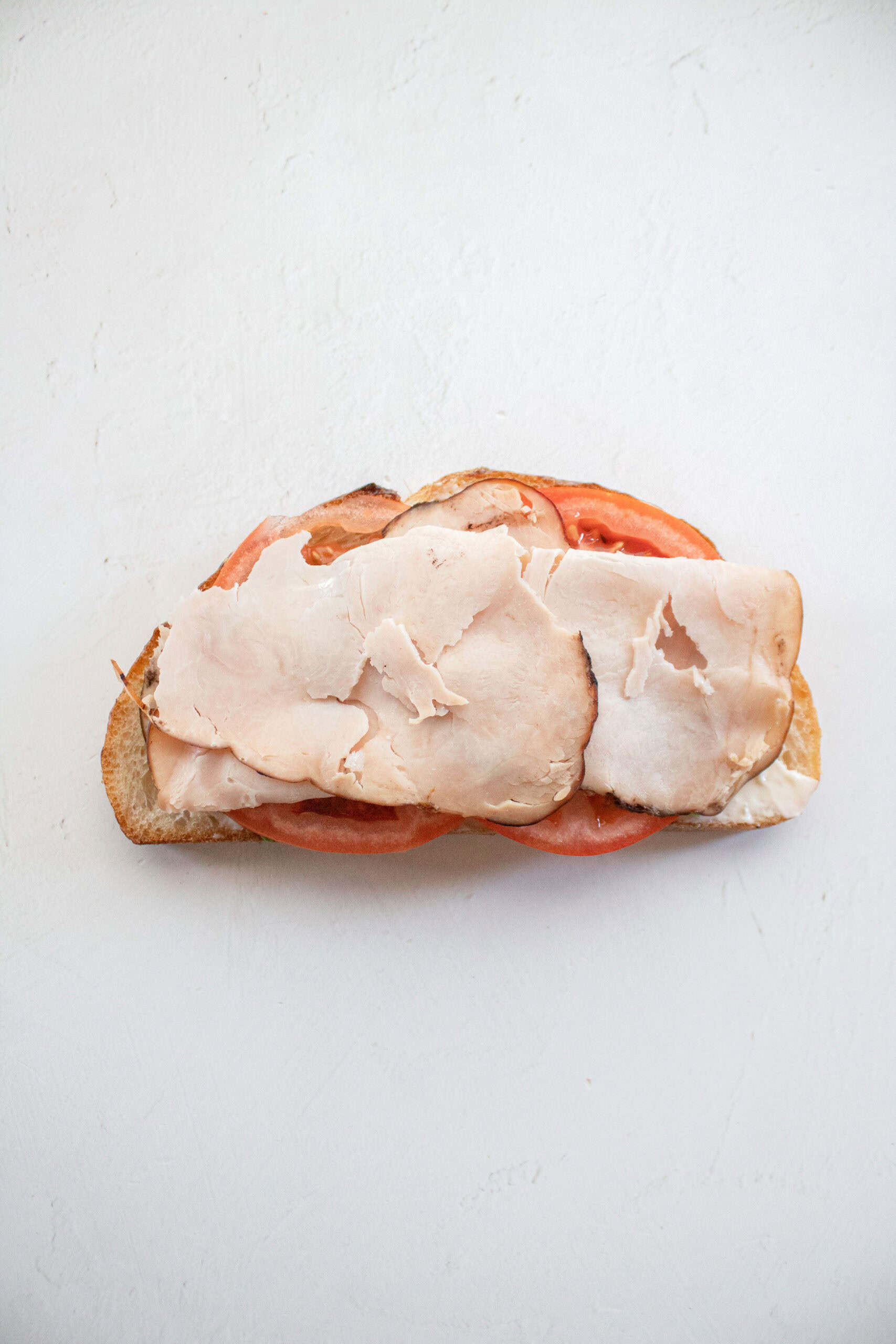 Sliced turkey on top of tomato on bread.