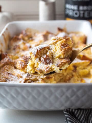 A scoop of french toast on a large spoon with powdered sugar dusted on top.