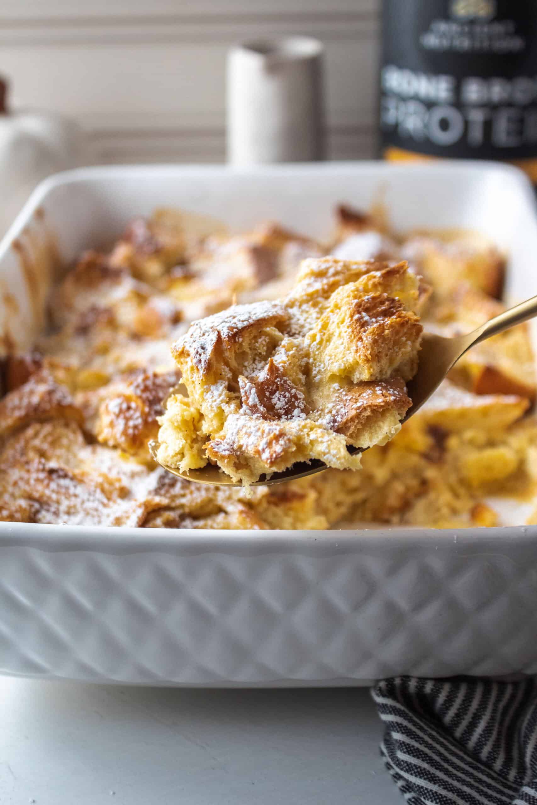 A scoop of french toast on a large spoon with powdered sugar dusted on top.
