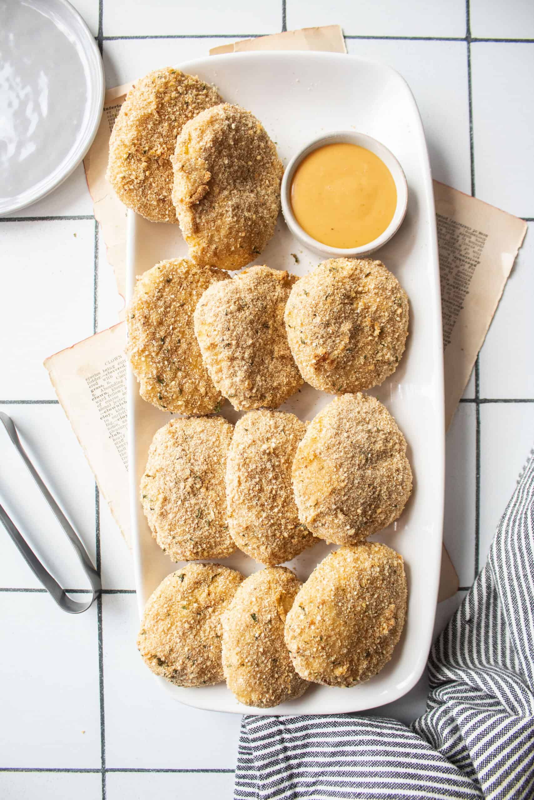 Air fryer chicken nuggets on a plate with dipping sauce.