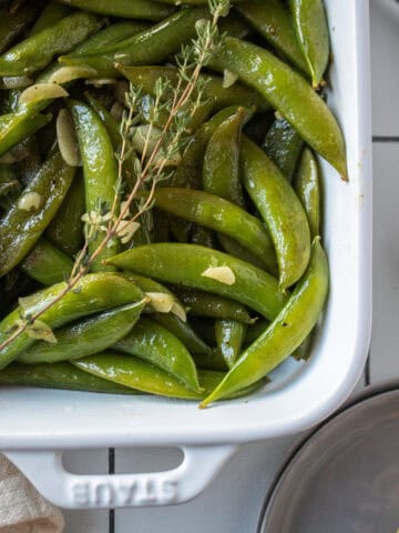Sautéed sugar snap peas in a dish with garlic, lemon, and thyme.