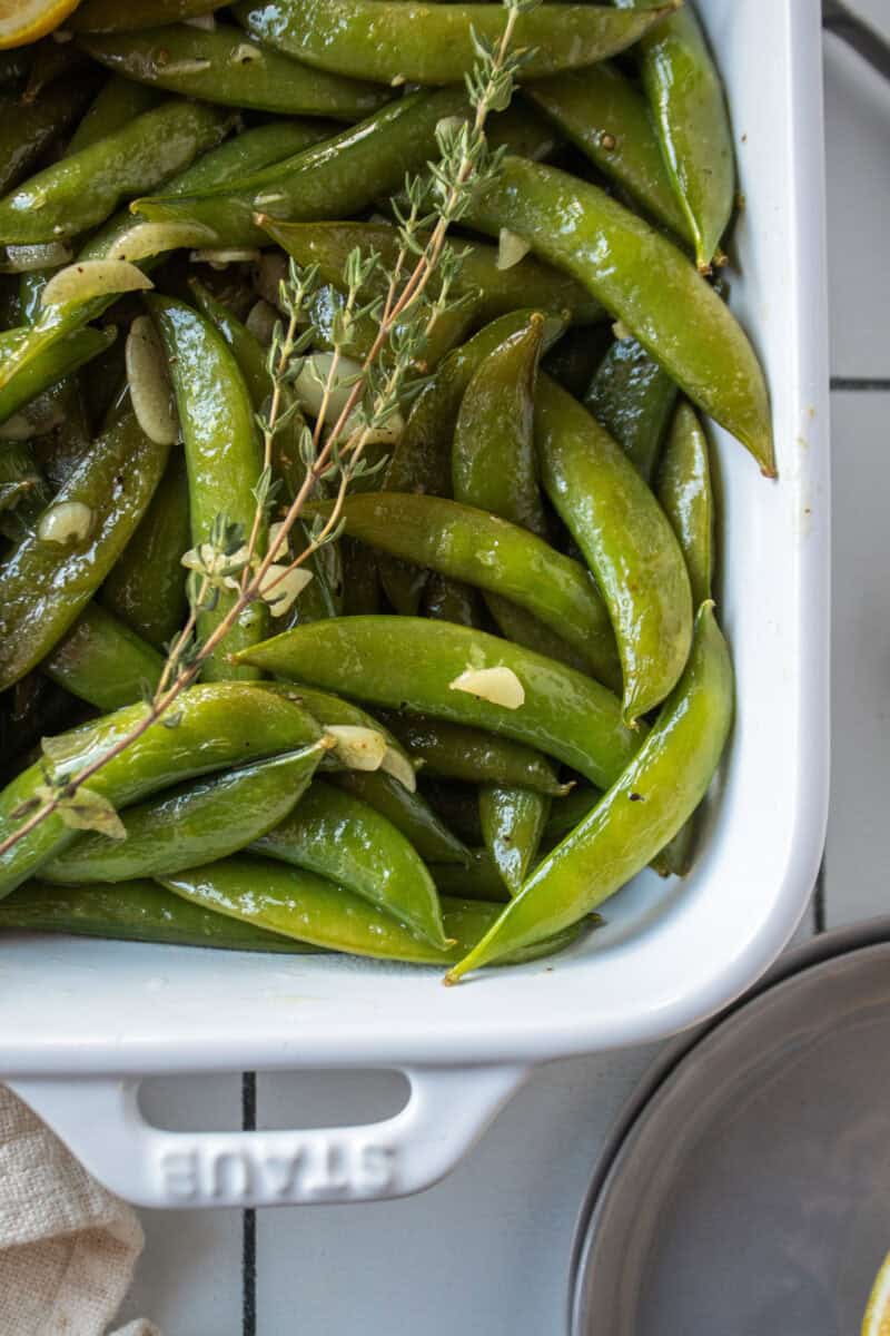 Saut&eacute;ed sugar snap peas in a dish with garlic, lemon, and thyme.