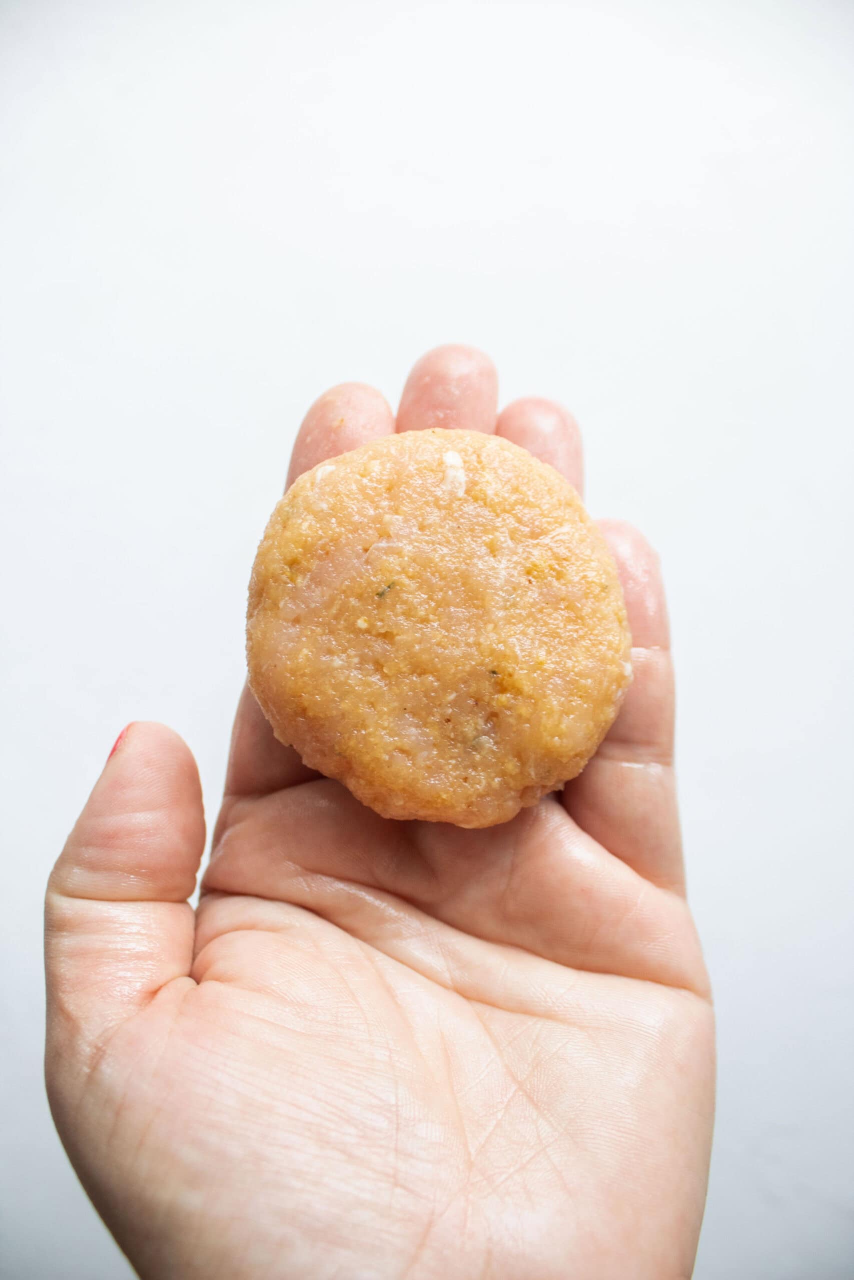 Chicken nugget patty in a hand.