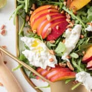 close up of nectarines and burrata on a bed of arugula.