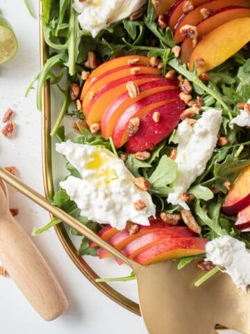 close up of nectarines and burrata on a bed of arugula.