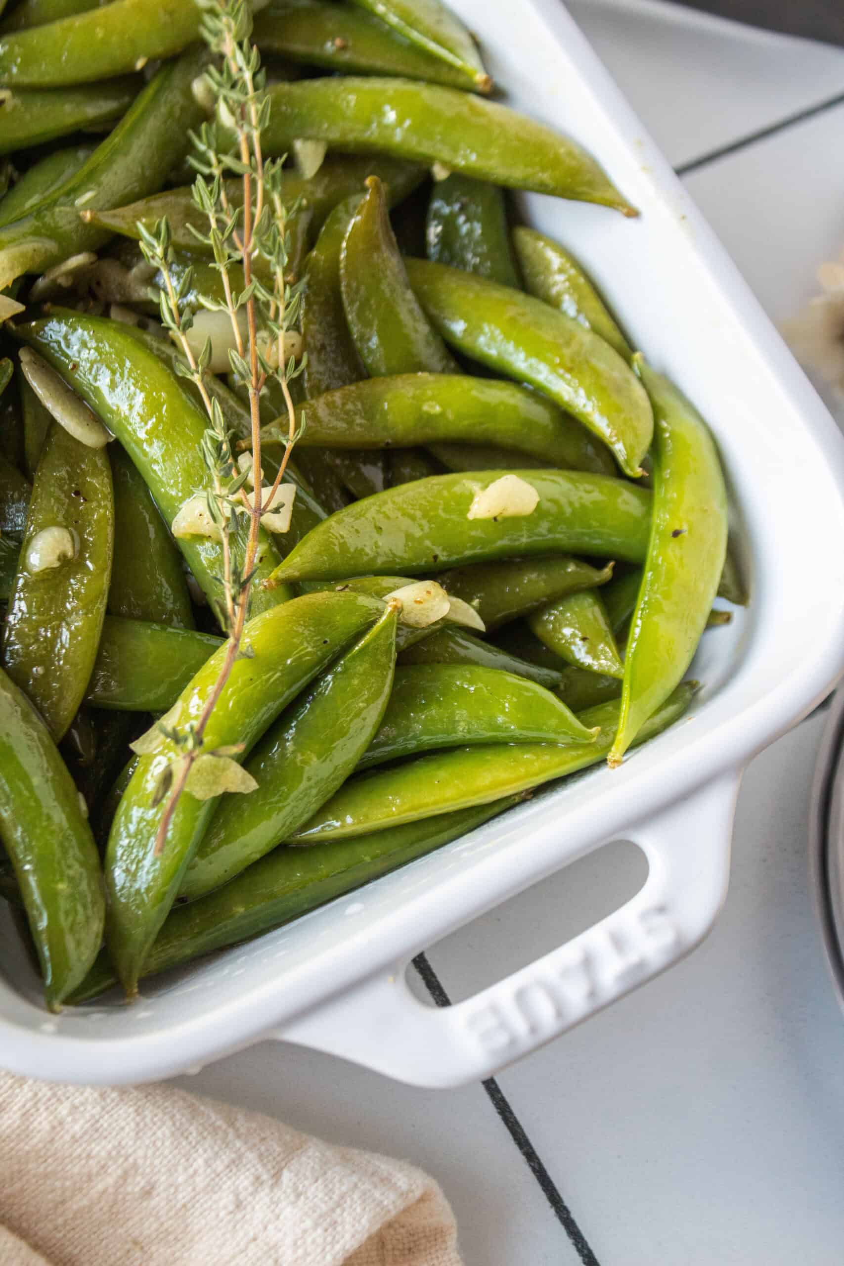 Sautéed sugar snap peas in a dish with garlic, lemon, and thyme.