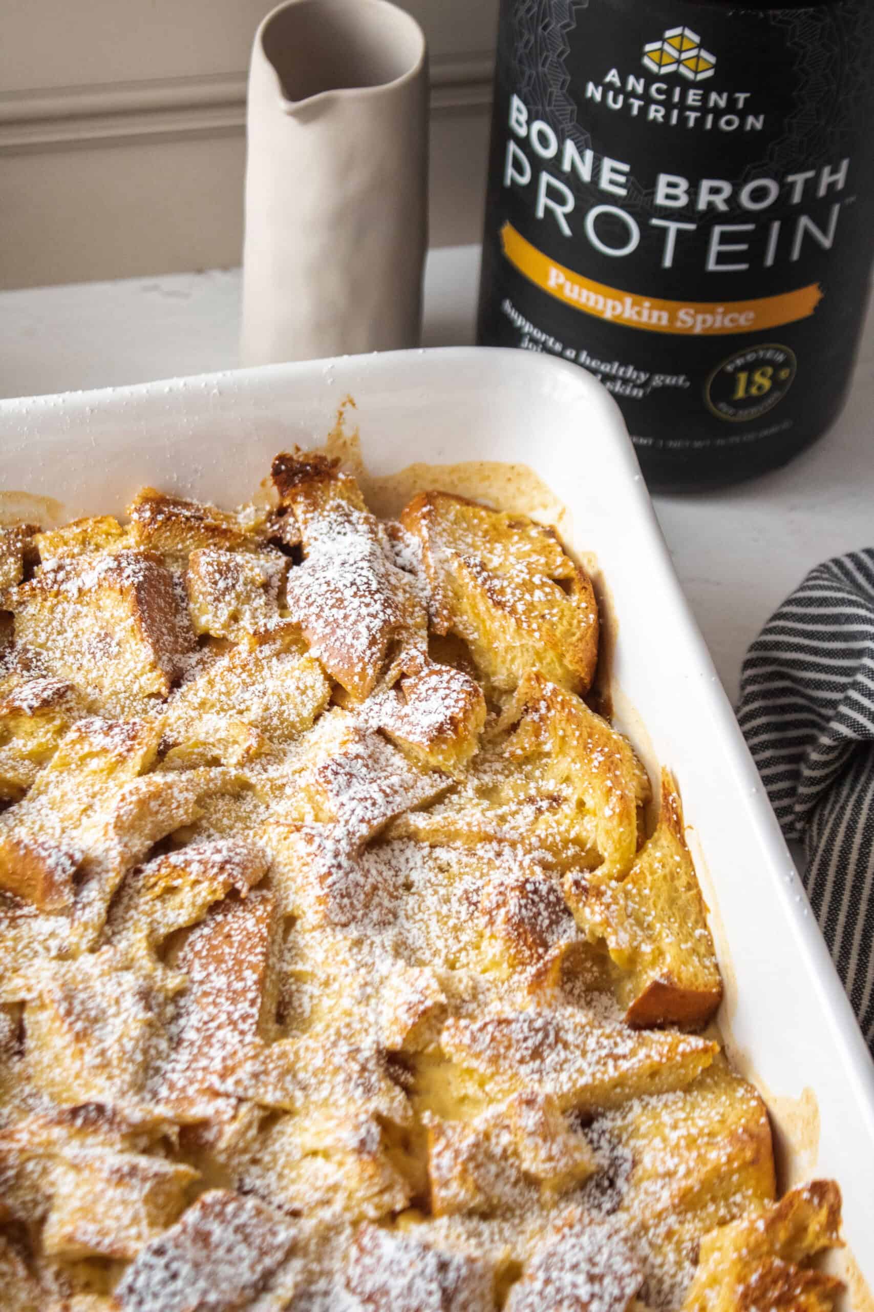 Corner of the casserole dish for pumpkin protein french toast with the bone broth protein powder container in the back.