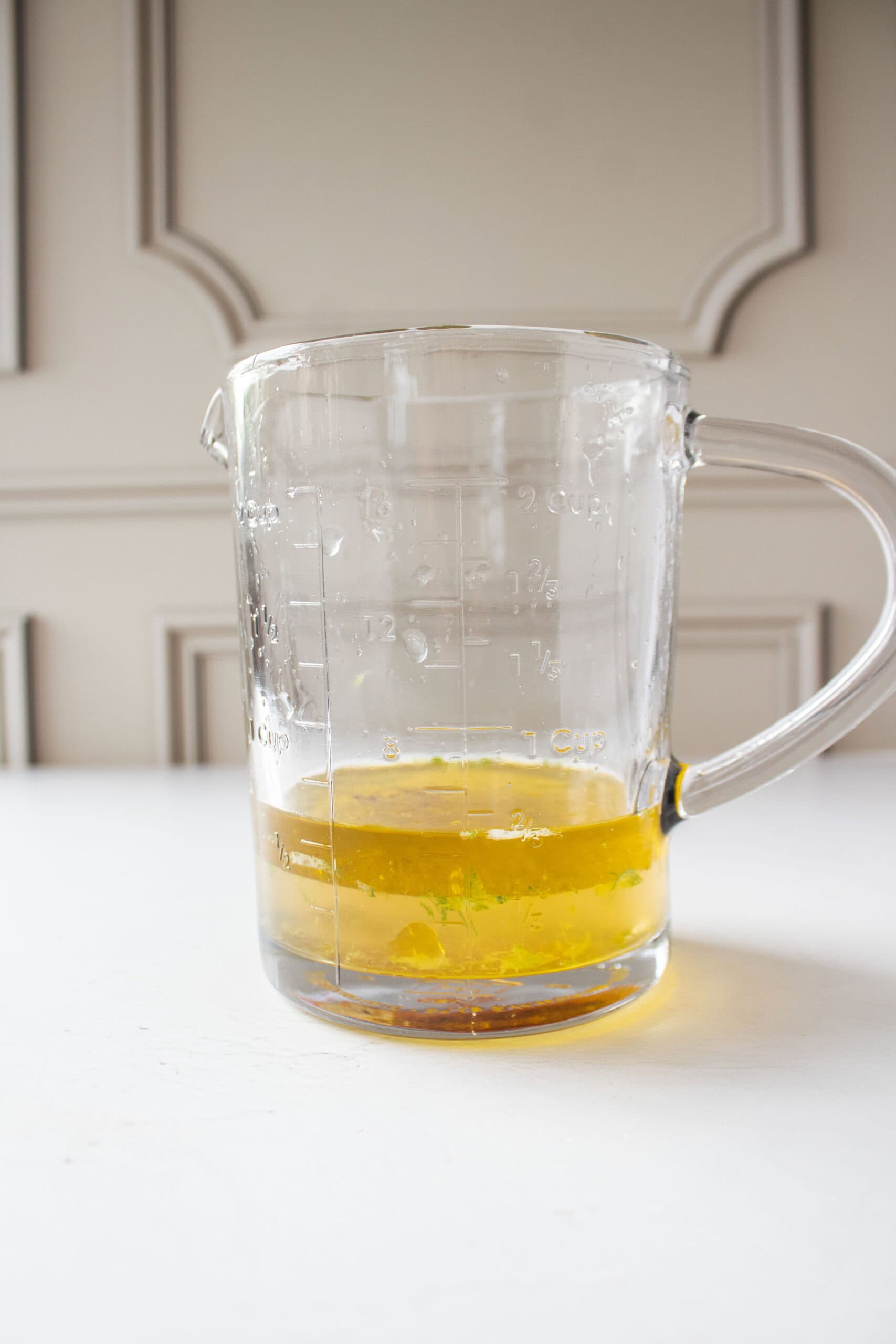 Lime juice, lime zest, honey, olive oil, white wine vinegar, salt and pepper in a measuring cup.