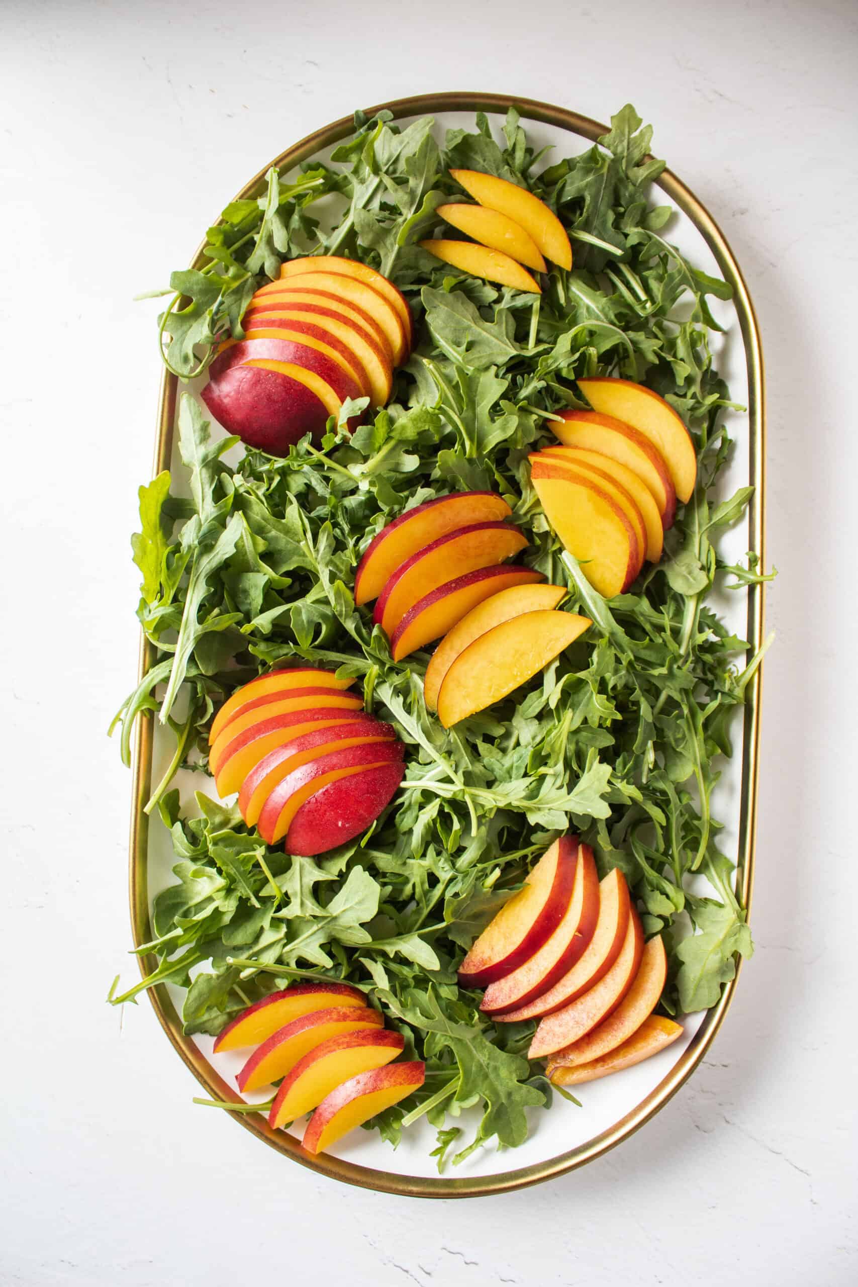 Nectarines and arugula on a platter.