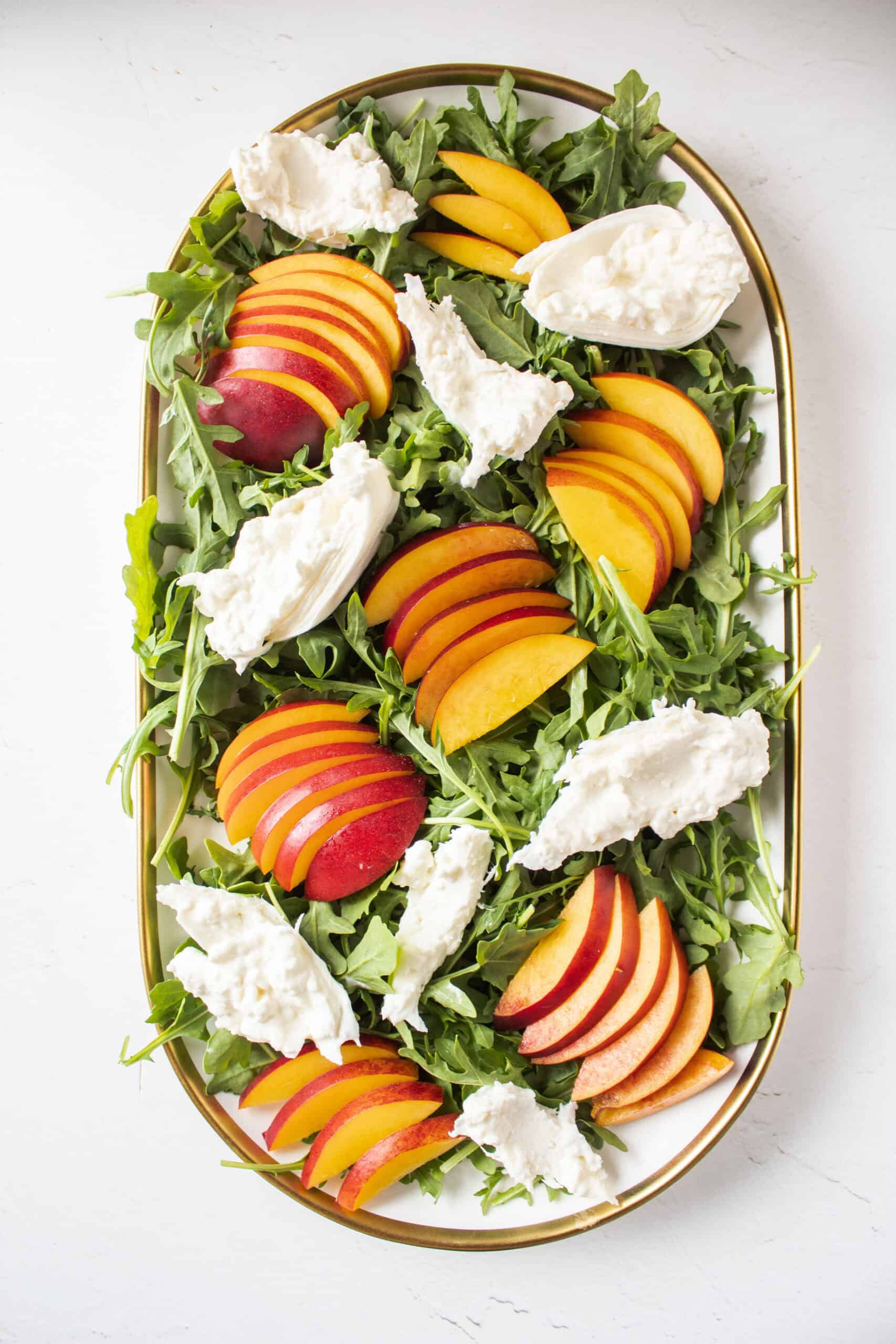 Nectarines and arugula on a platter with burrata