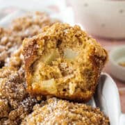 The inside of an apple streusel muffin leaning on its side on top of another muffin in a basket.