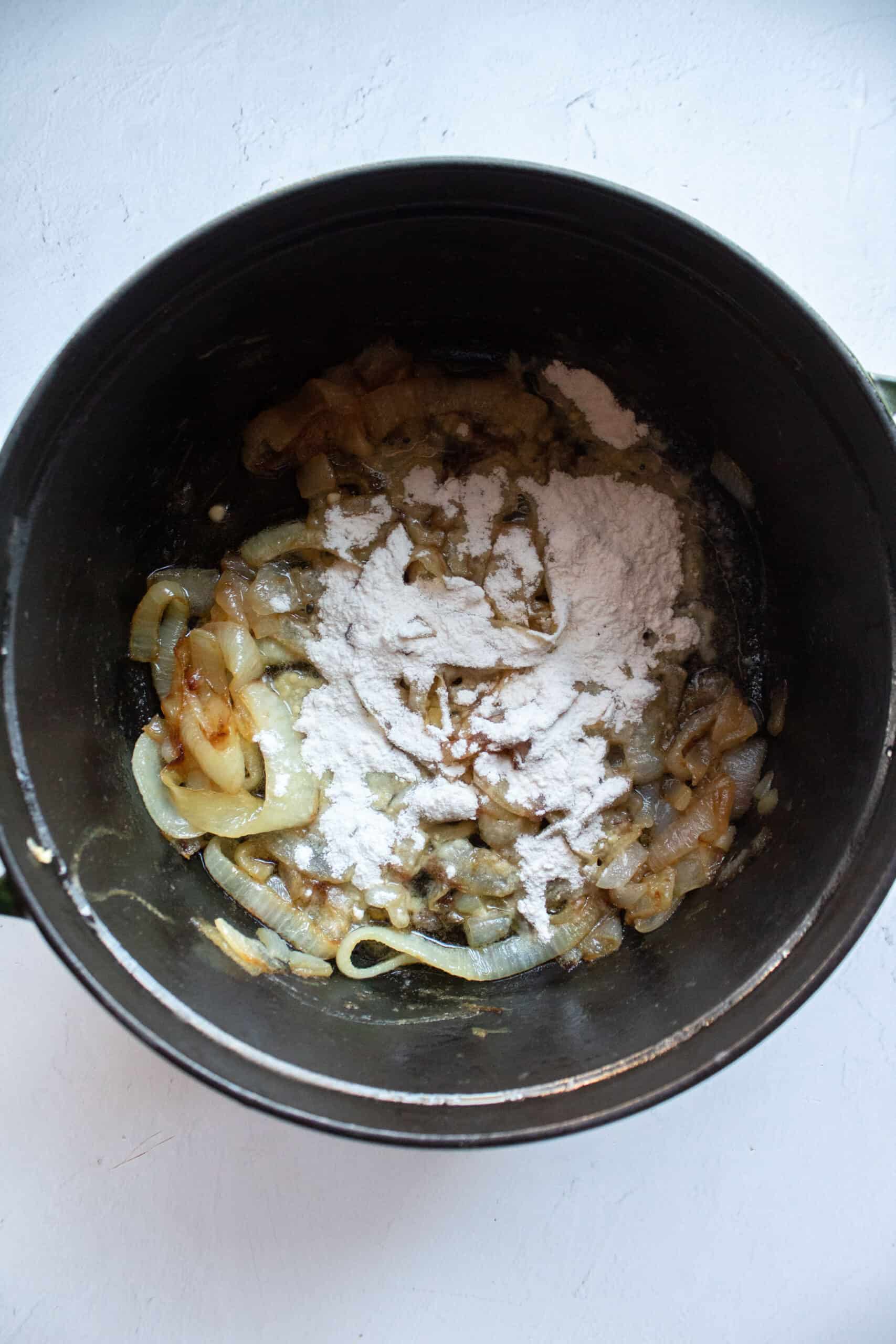 Flour added to a dutch oven of caramelized onions.