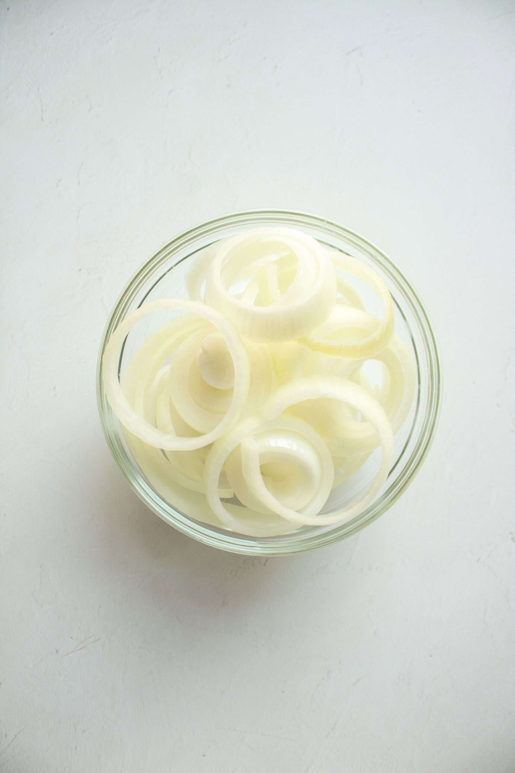 Sliced raw onions in a small bowl.