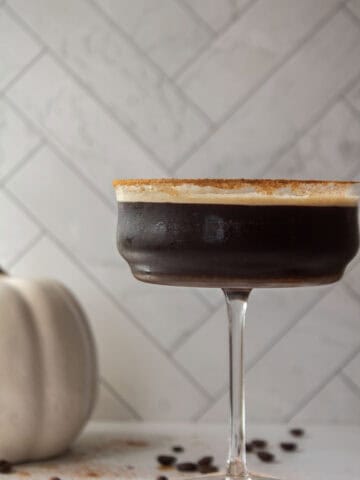 Straight on shot for a pumpkin spice espresso martini in a coupe glass with a rim of pumpkin pie spice.