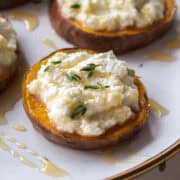 High angle shot of a sweet potato round topped with ricotta, thyme, and honey on a plate surrounded by other sweet potato rounds.