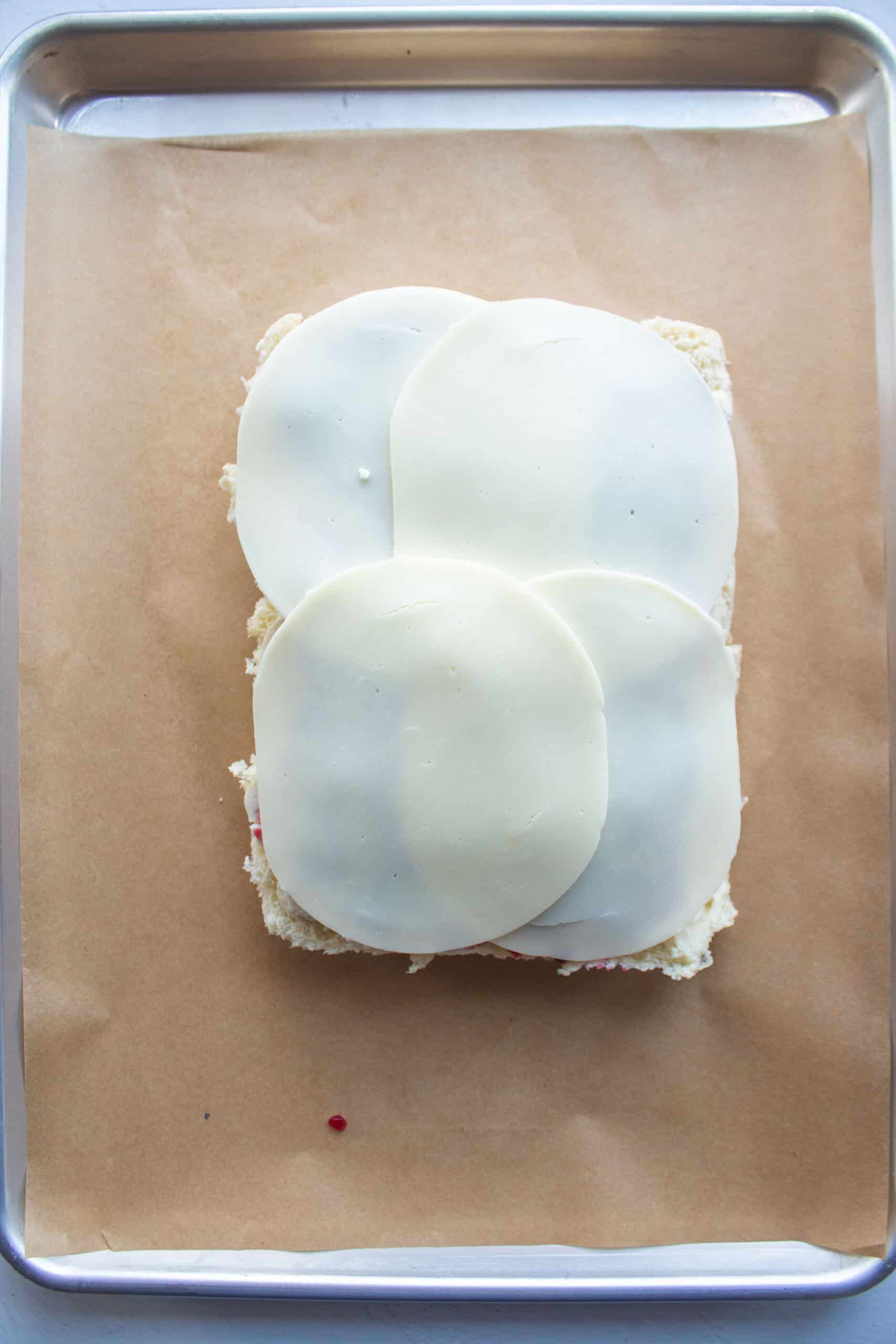 Provolone cheese slices on top of sliced roasted turkey and cranberry sauce over the bottoms of hawaiian rolls.