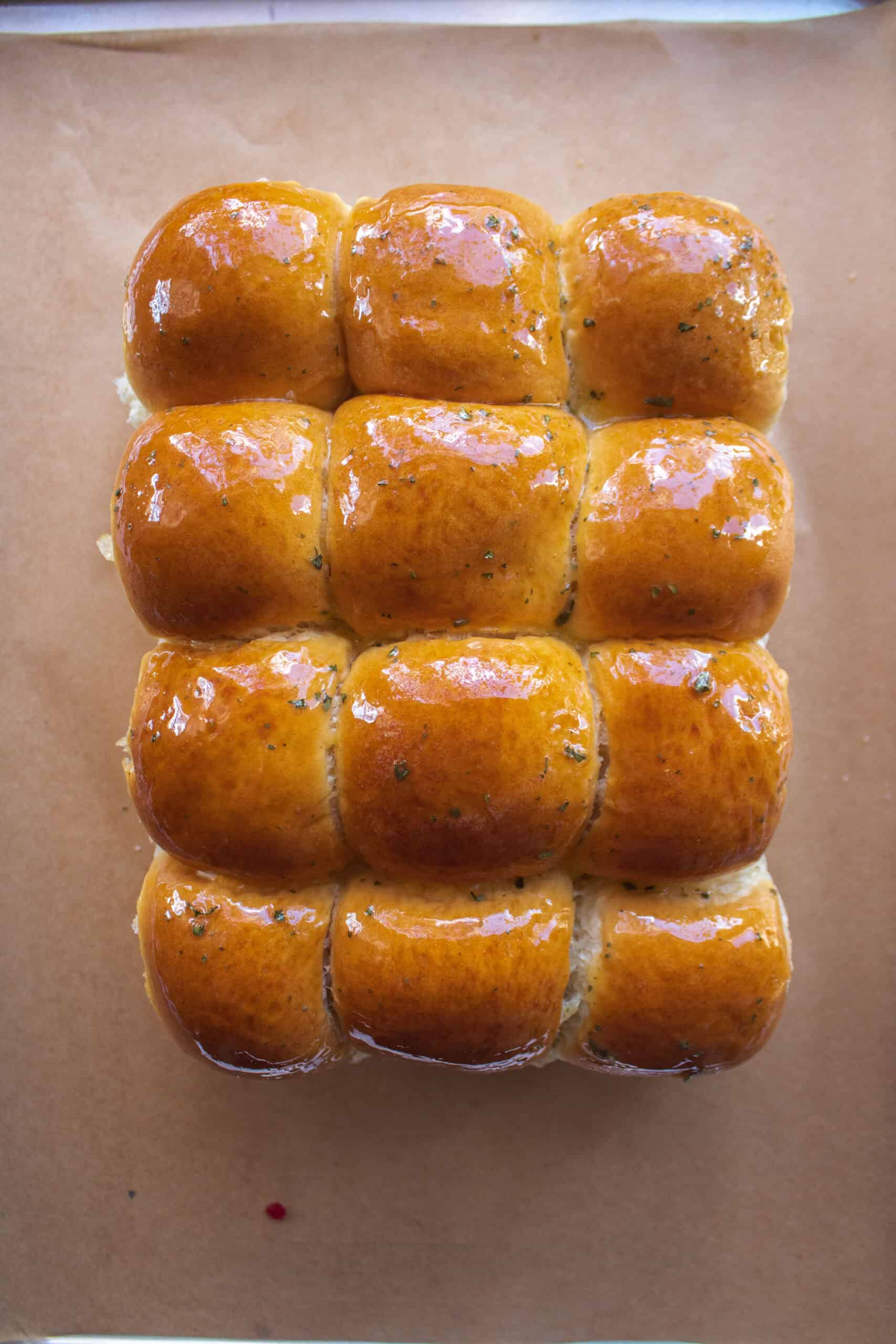 The tops of hawaiian rolls on top of sliced turkey, cranberry sauce, and provolone cheese brushed with melted butter and parsley.