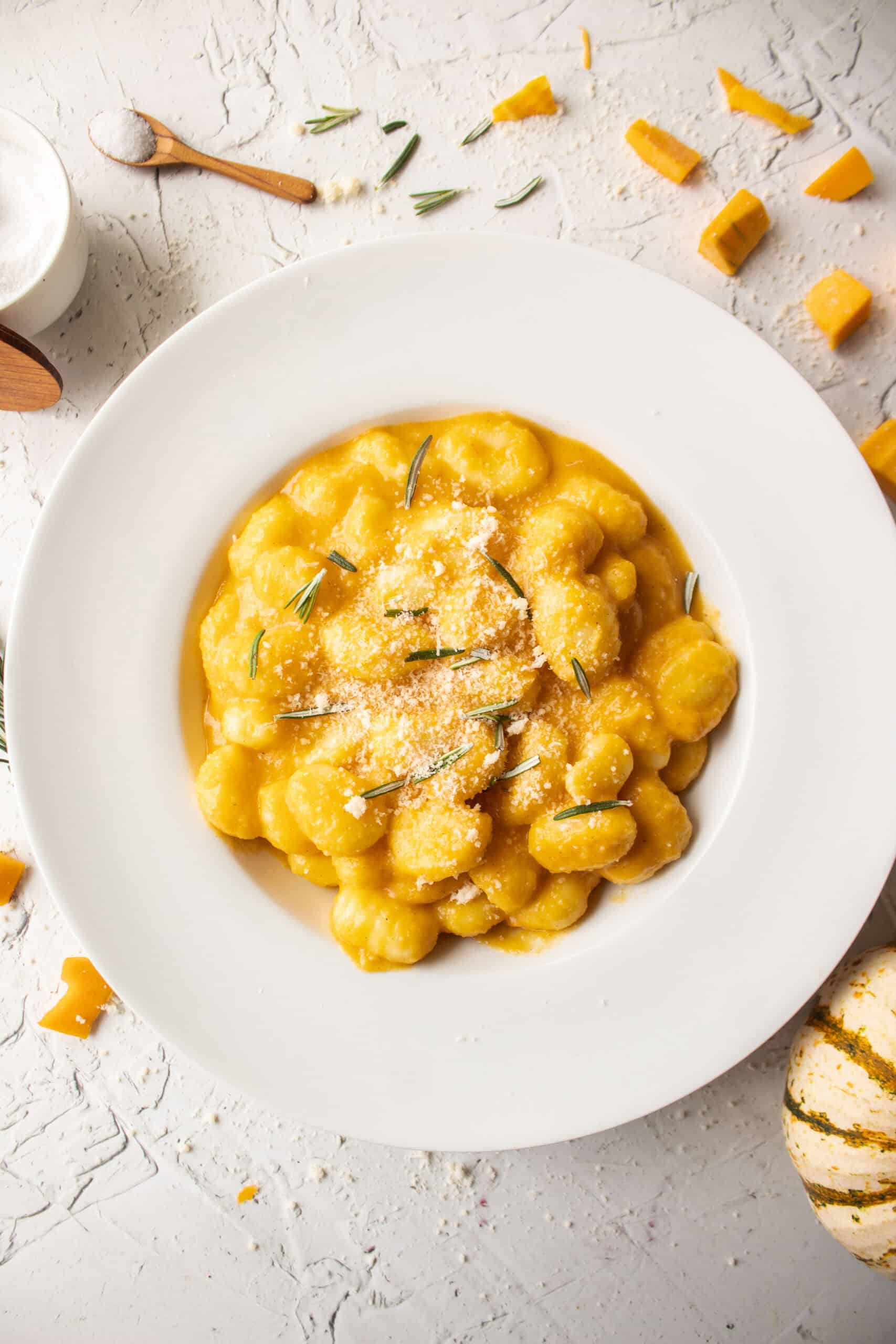 Butternut squash pasta gnocchi in a bowl topped with parmesan cheese and rosemary.