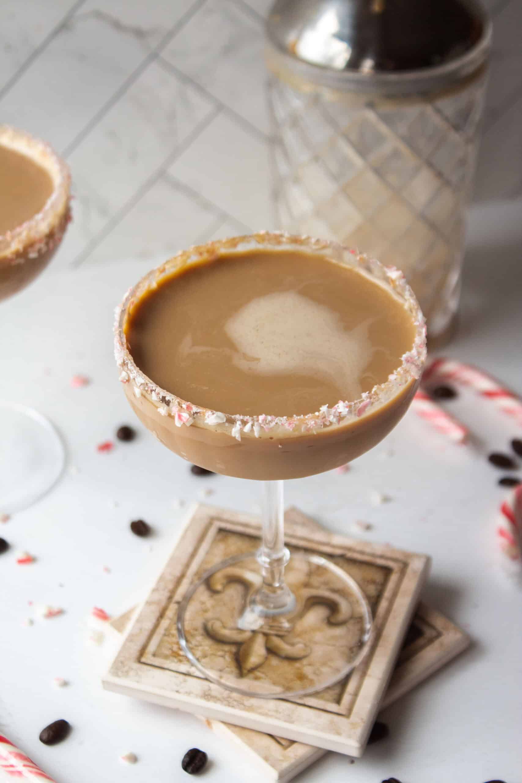 Chocolate peppermint espresso martini in a coupe glass rimmed with crushed candy canes on coasters.