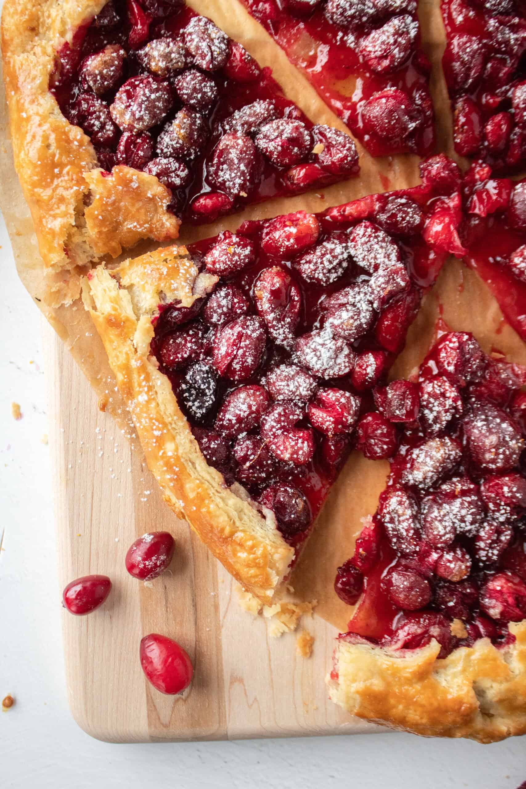 A slice of a cranberry orange galette on a serving board.