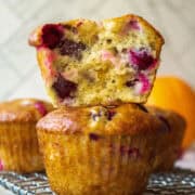 Close up of the inside of a cranberry orange muffin stacked on top of another muffin on a rack.