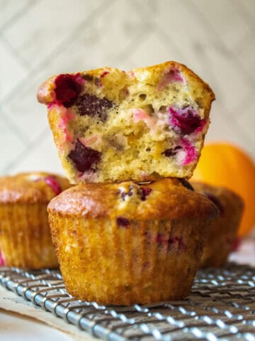 Close up of the inside of a cranberry orange muffin stacked on top of another muffin on a rack.