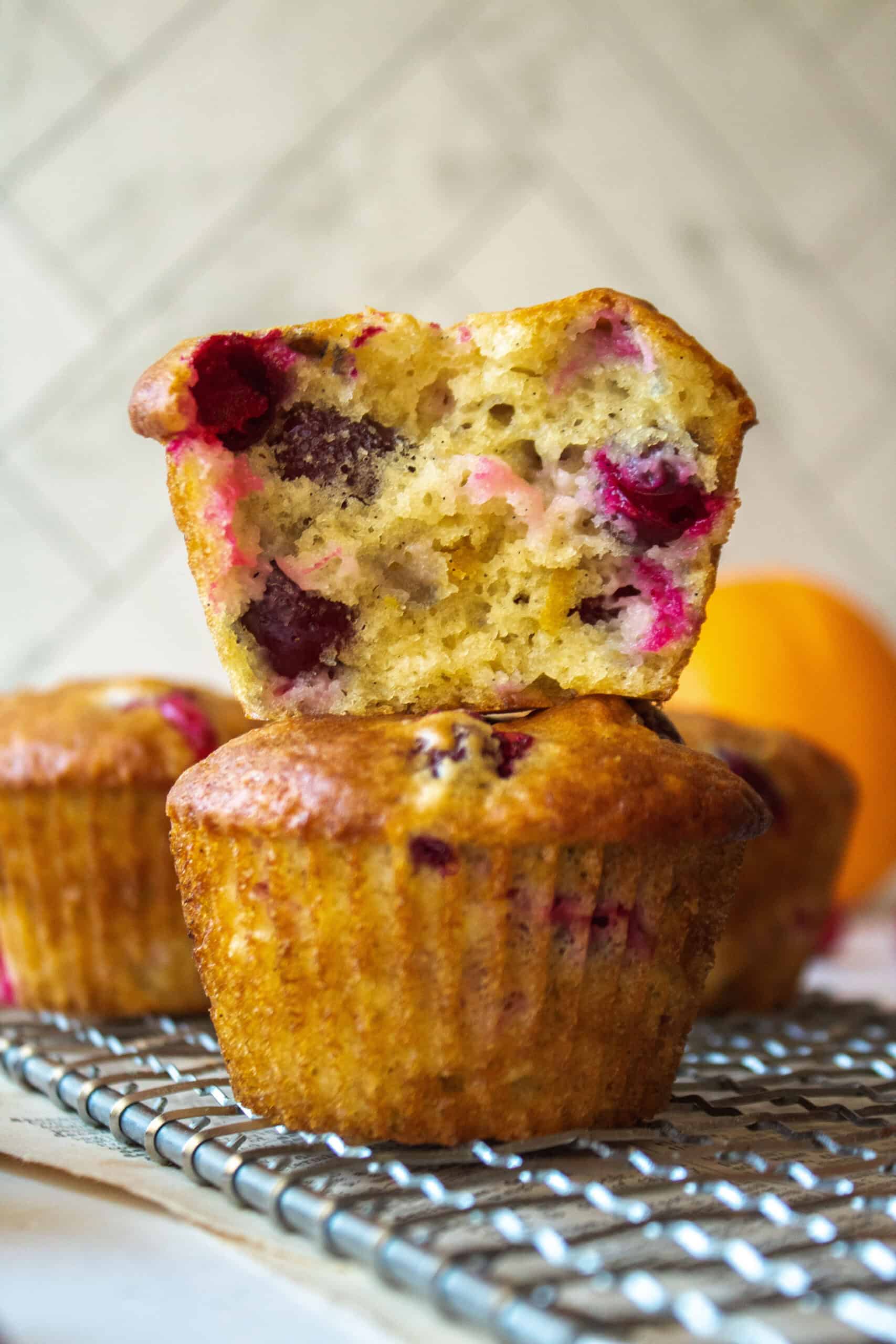 Close up of the inside of a cranberry orange muffin stacked on top of another muffin on a rack.