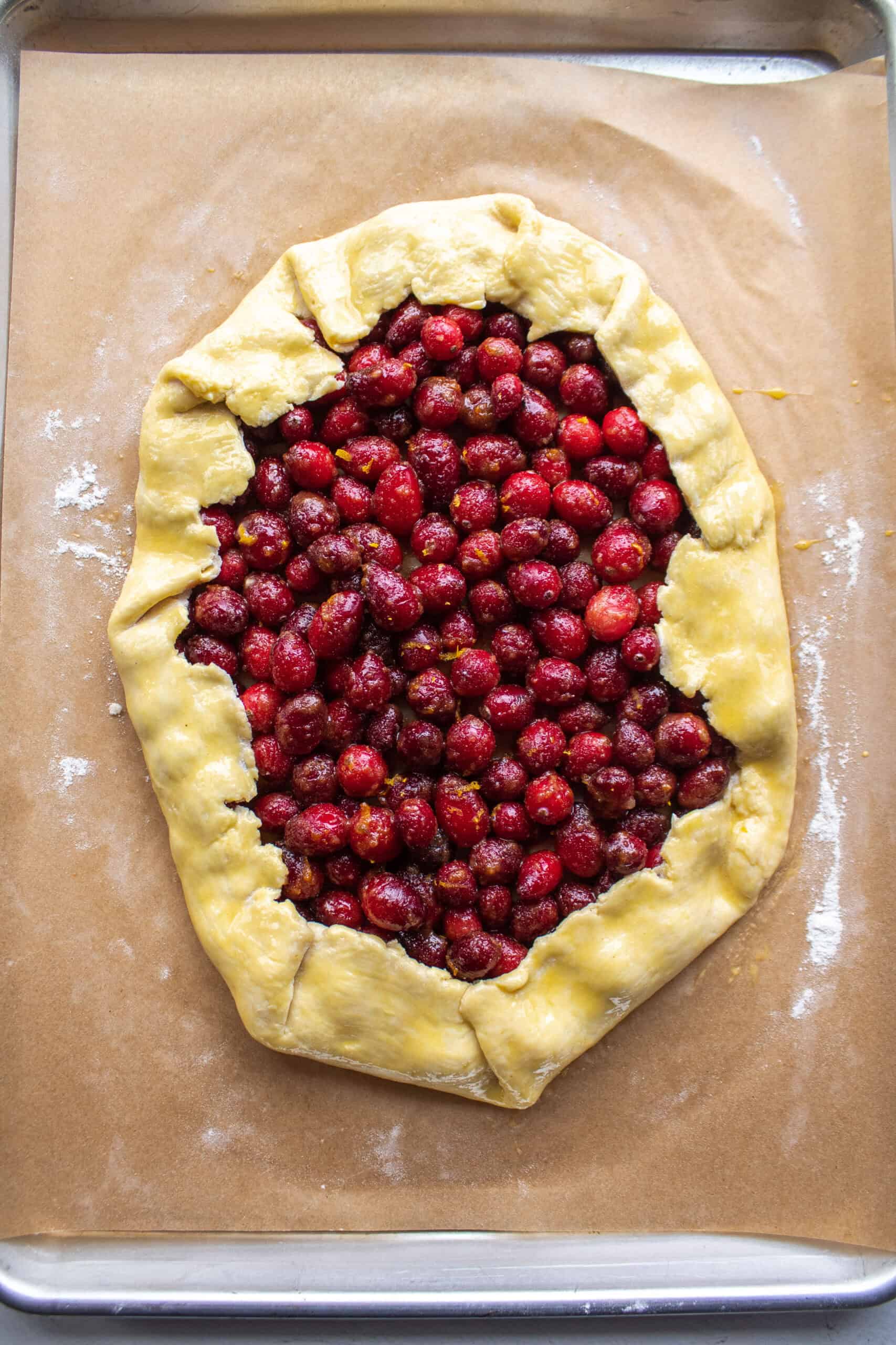 Cranberries folded into a galette pastry dough with the sides of the dough folded over and brushed with eggwash.