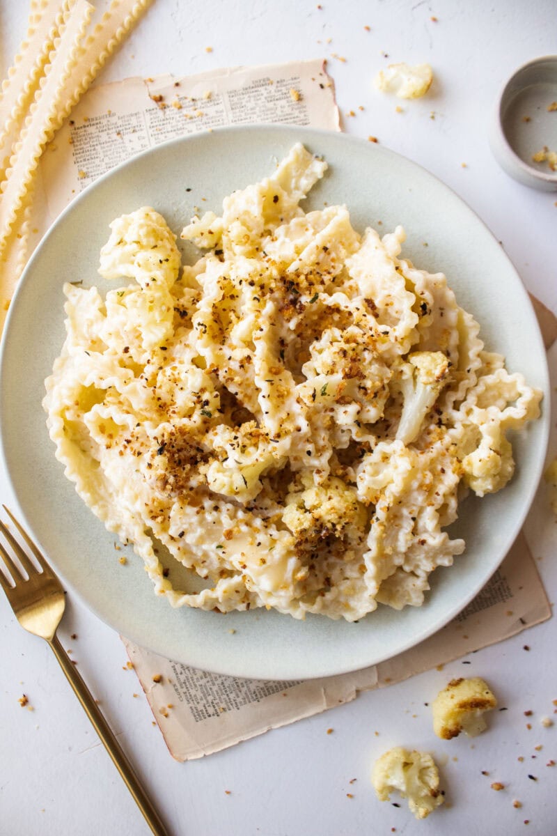 Creamy pasta with roasted cauliflower tossed in a parmesan sauce topped with toasted panko breadcrumbs on a plate.