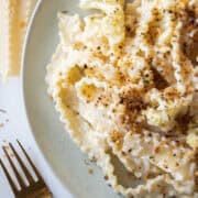 Creamy pasta with roasted cauliflower tossed in a parmesan sauce topped with toasted panko breadcrumbs on a plate.