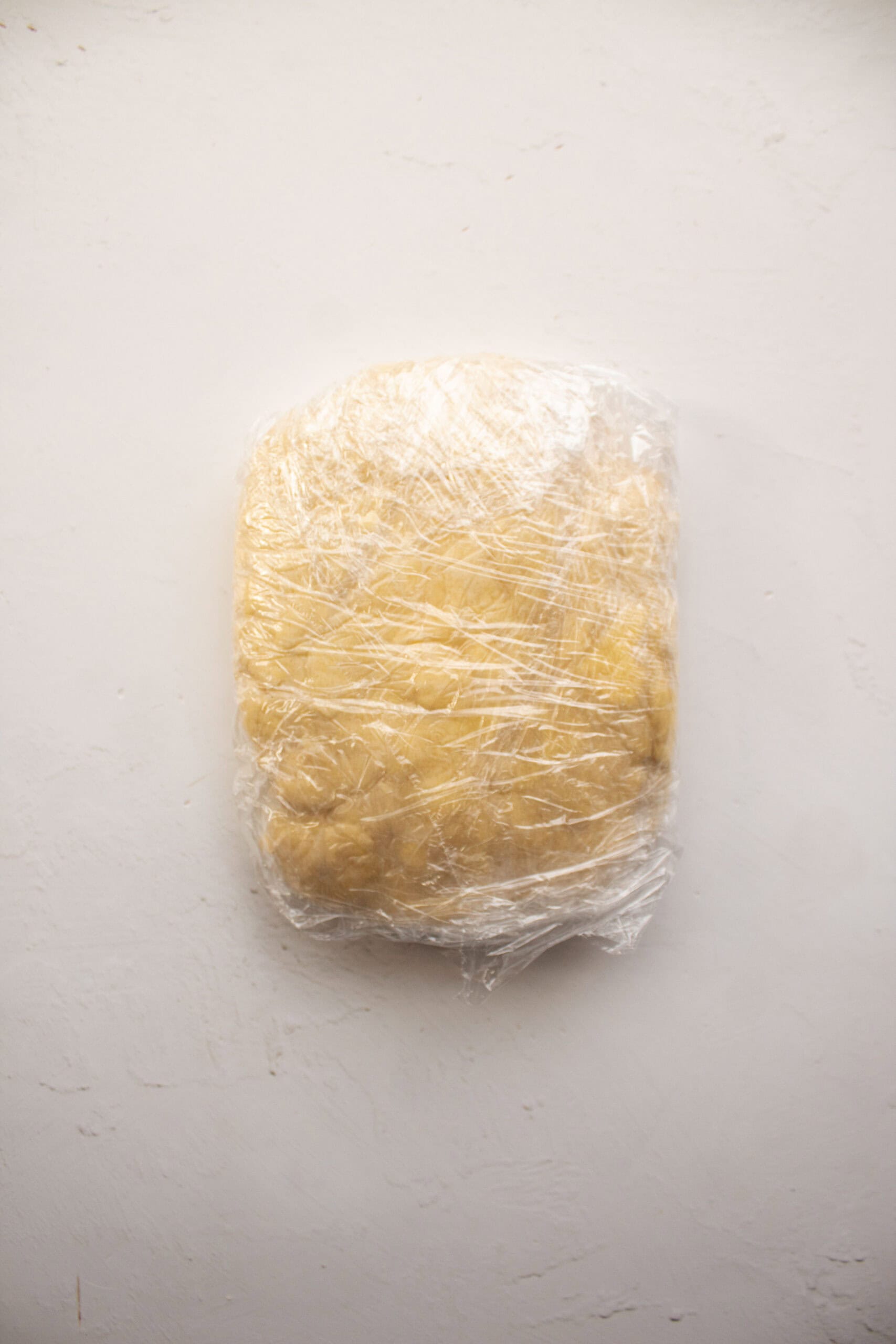 Fresh kneaded pastry dough wrapped in plastic wrap.