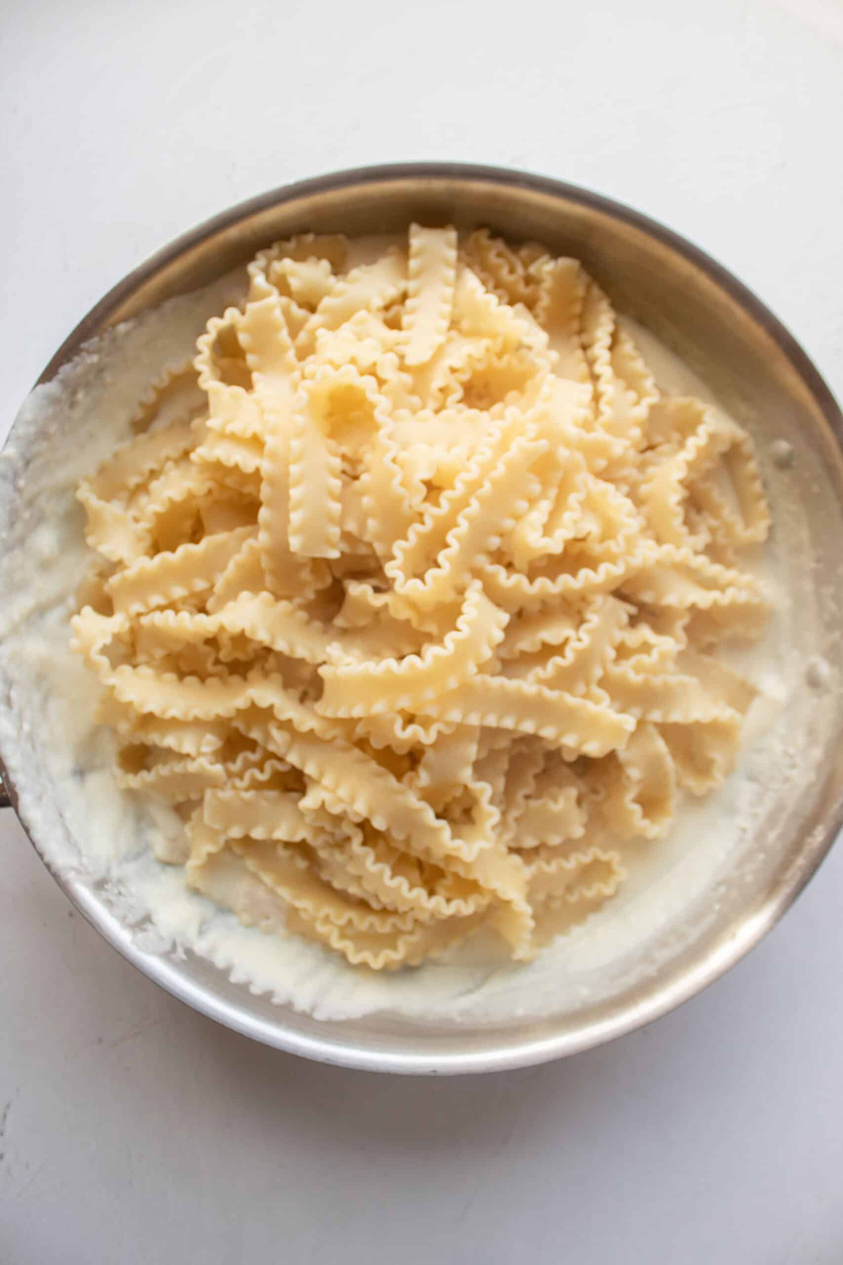 Malfadine pasta in a large skillet with a parmesan cream sauce.
