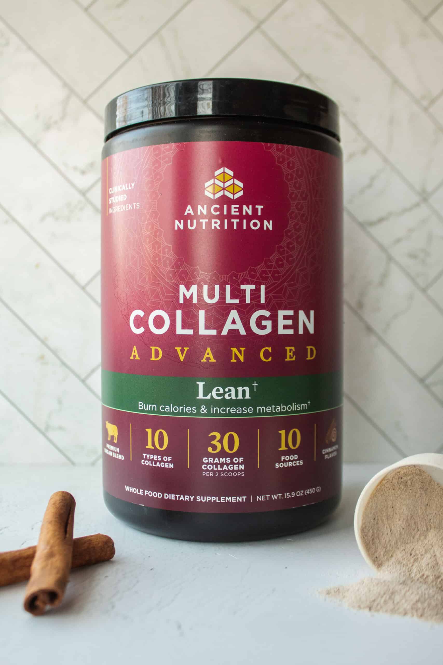 A tub of Ancient Nutrition Multi Collagen Advanced Lean with some protein powder spilled out and cinnamon sticks in the front.