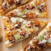 Close up of a slice of barbecue chicken flatbread on a serving board.