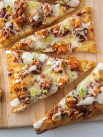 Close up of a slice of barbecue chicken flatbread on a serving board.