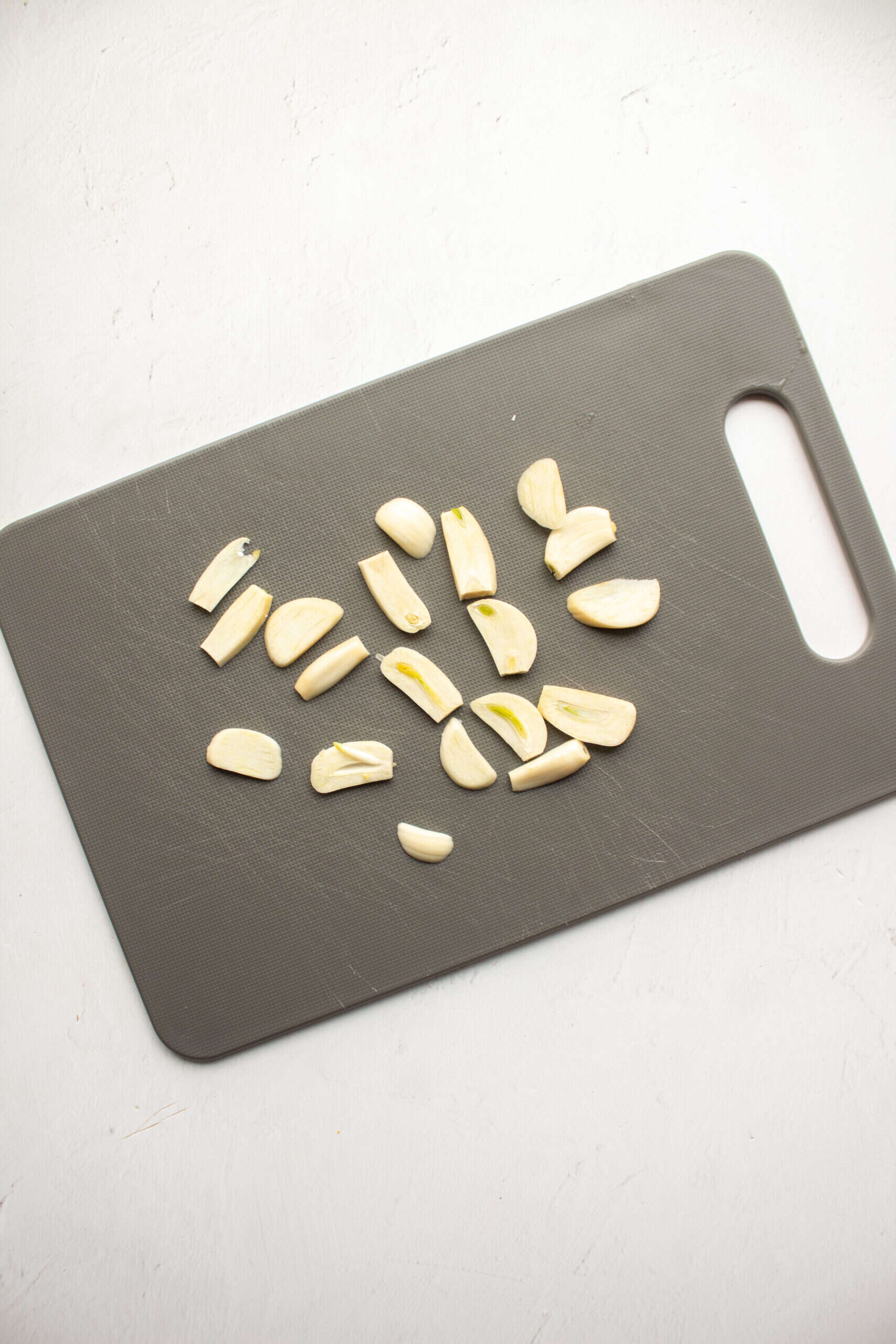 Fresh garlic cloves sliced on a gray cutting board for flavorful cooking ingredients.