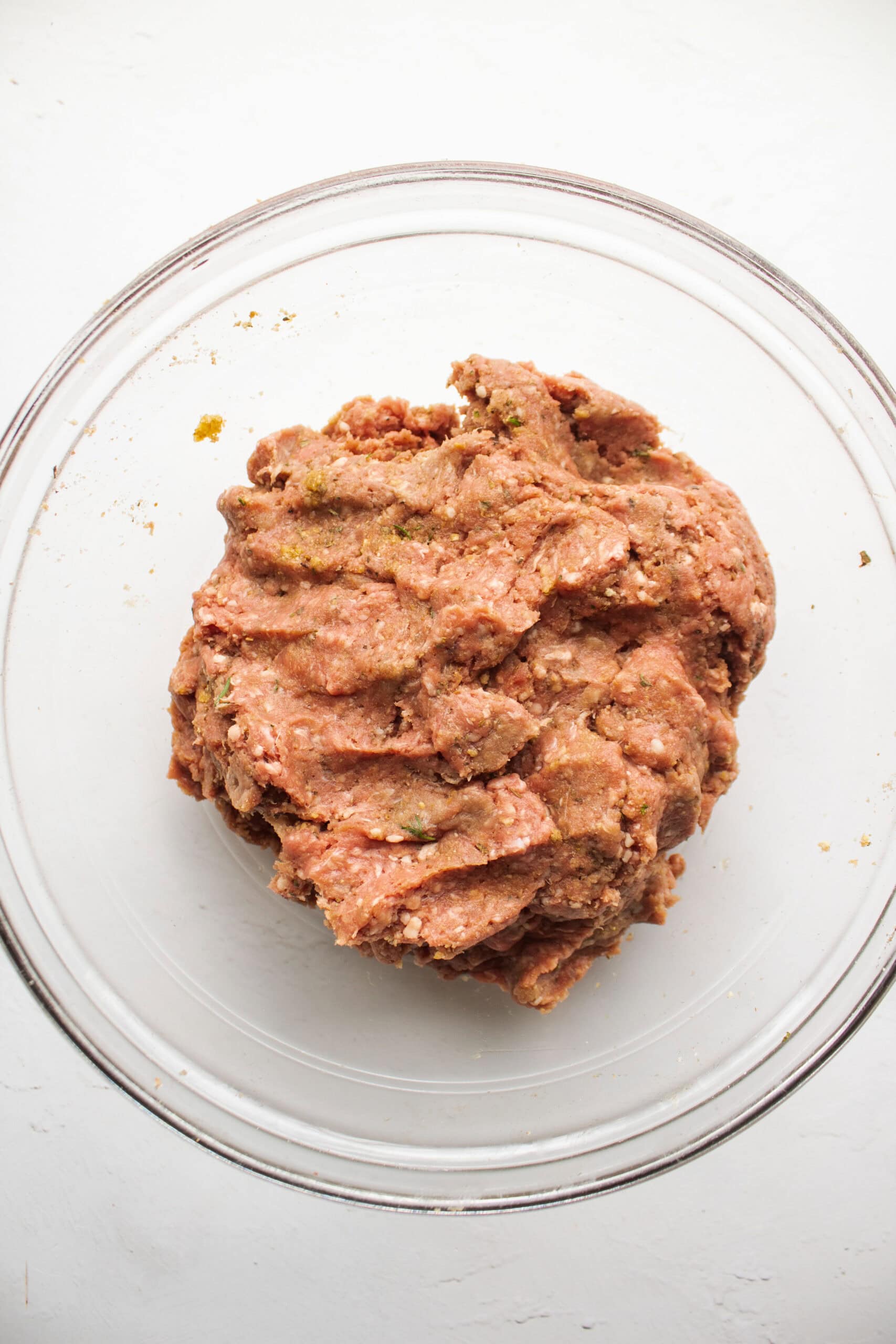 Ground beef mixture in a large mixing bowl before assembling into meatballs.
