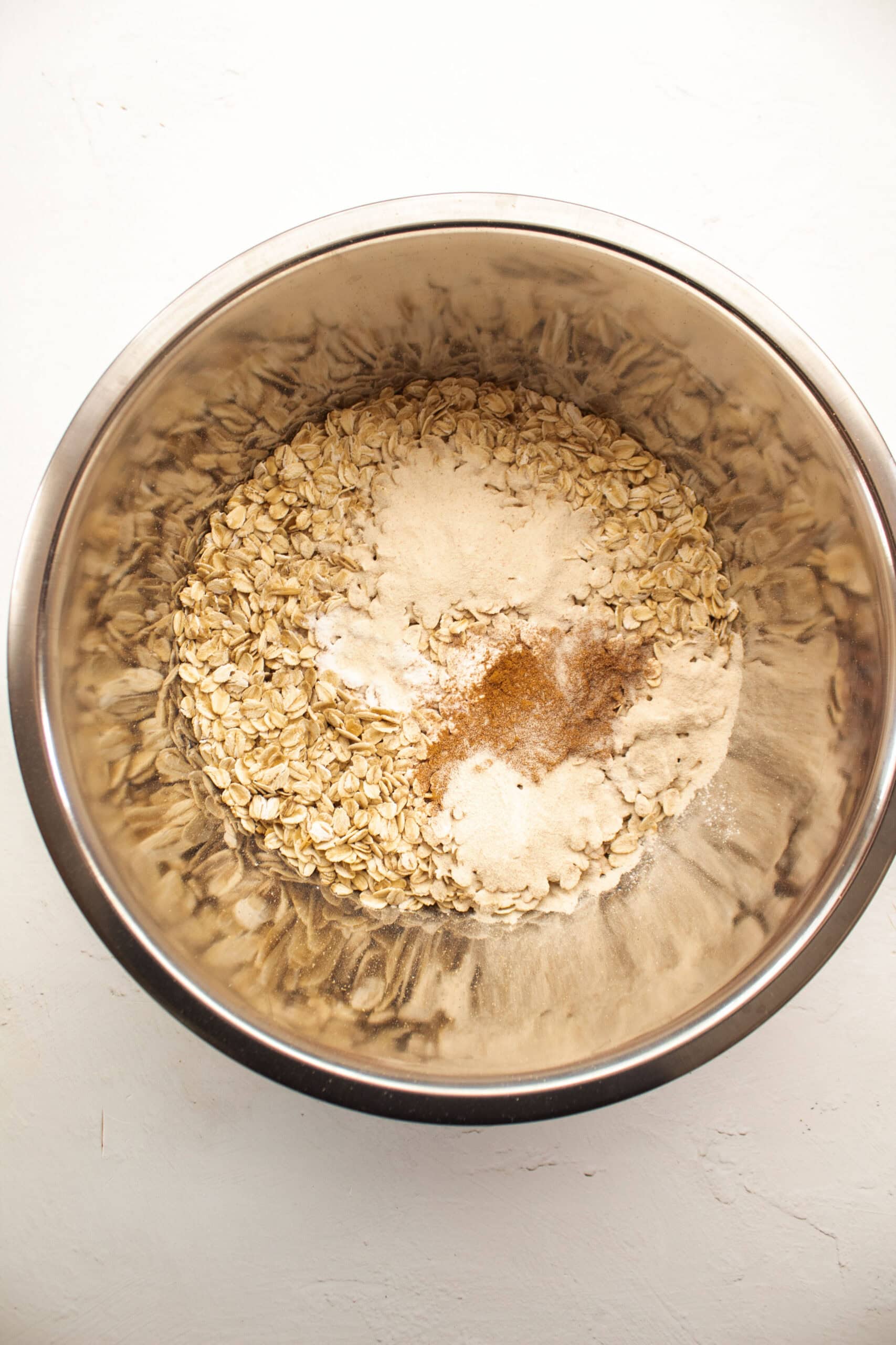 Rolled oats cinnamon, baking powder, salt, in a large aluminum bowl.