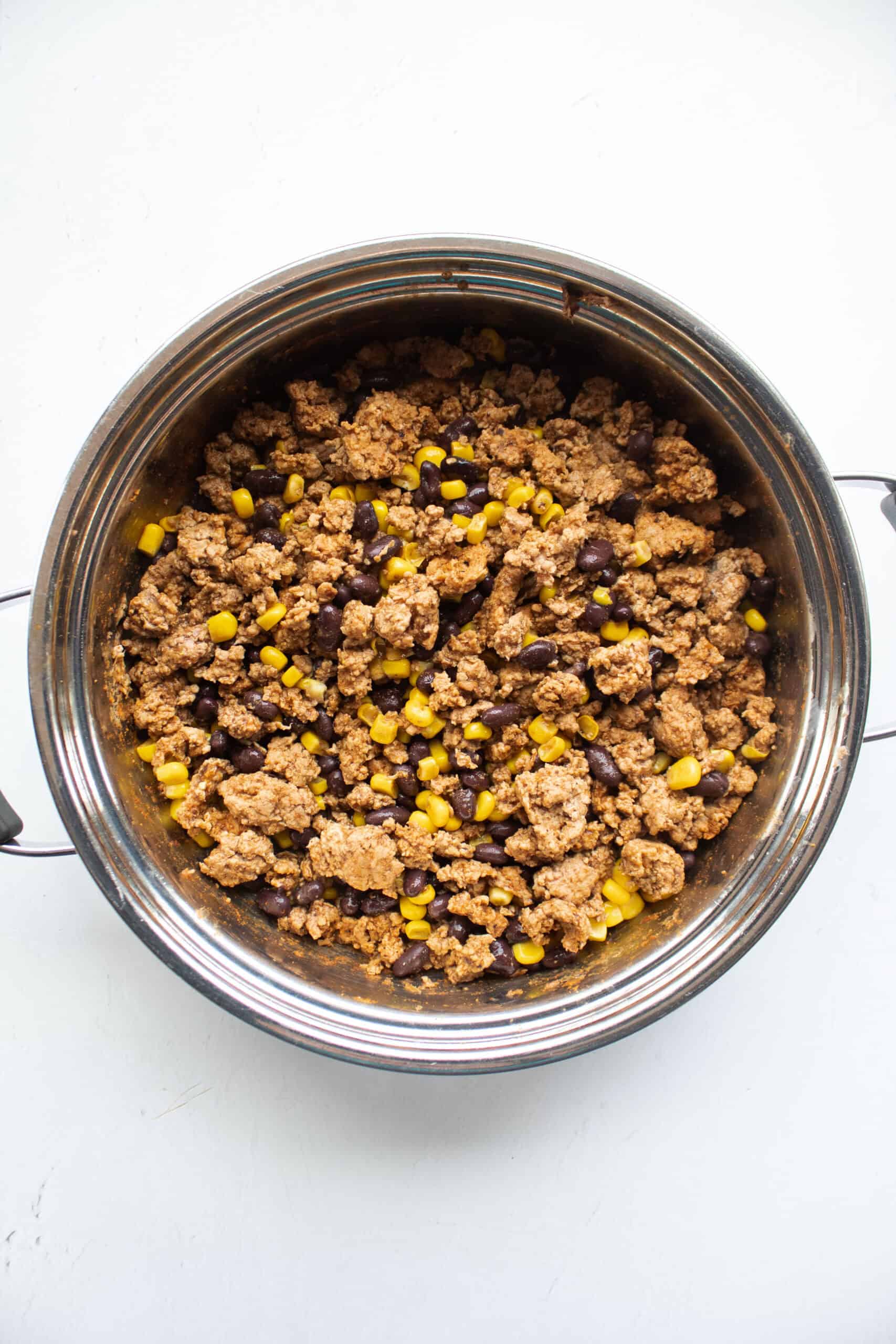 Seasoned ground turkey in a skillet with corn and black beans.