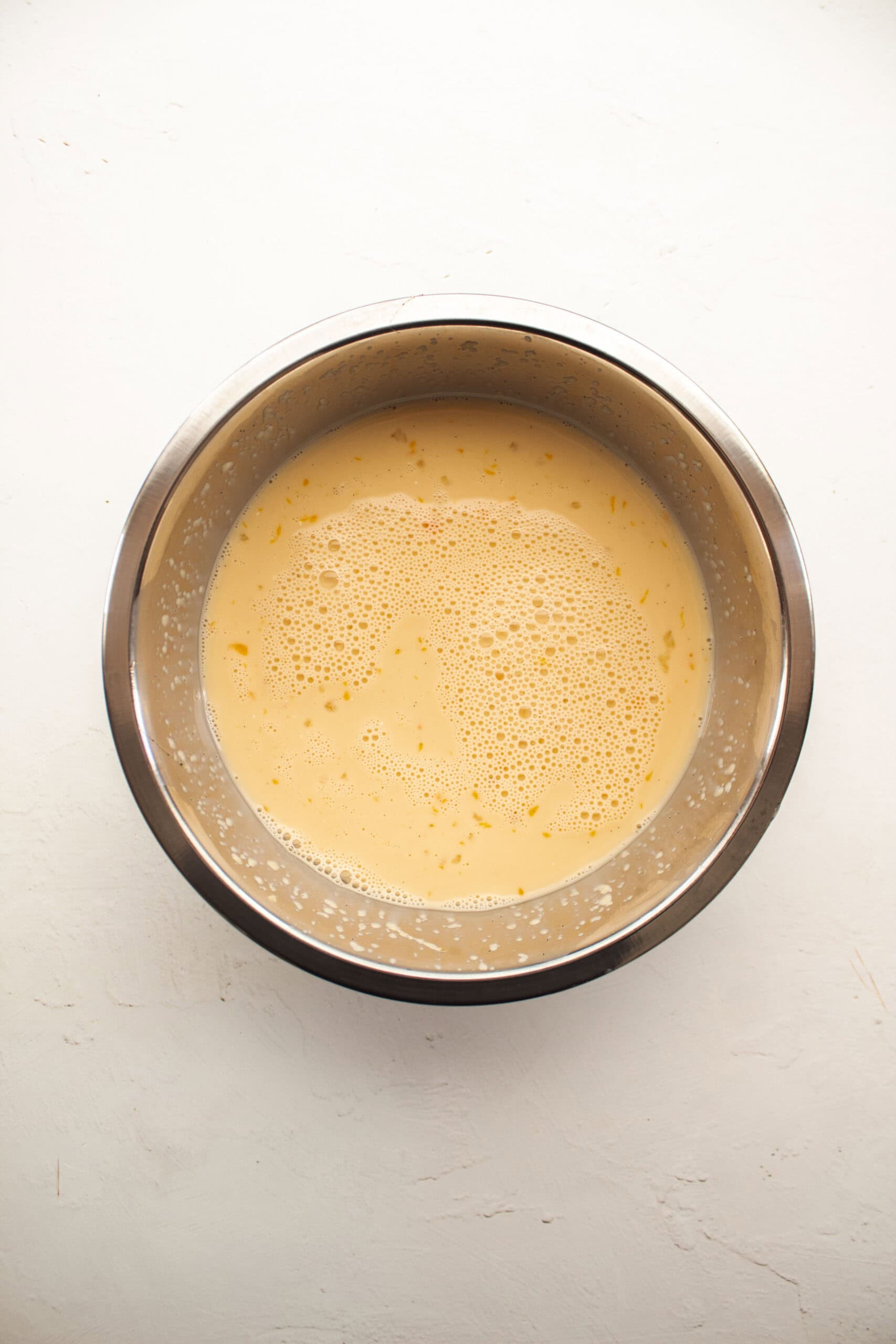 Whisked egg, vanilla, applesauce, milk, and maple syrup in a small aluminum bowl.