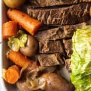 Close up of corned beef and cabbage on a platter with carrots, potatoes.