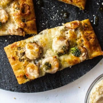 Close up of a piece of chicken sausage and pesto flatbread on a platter.