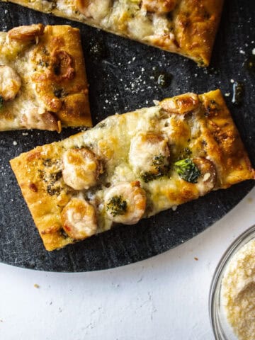 Close up of a piece of chicken sausage and pesto flatbread on a platter.