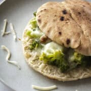 Broccoli pita melt on a sandwich with a close up of crispy bread and cheese.