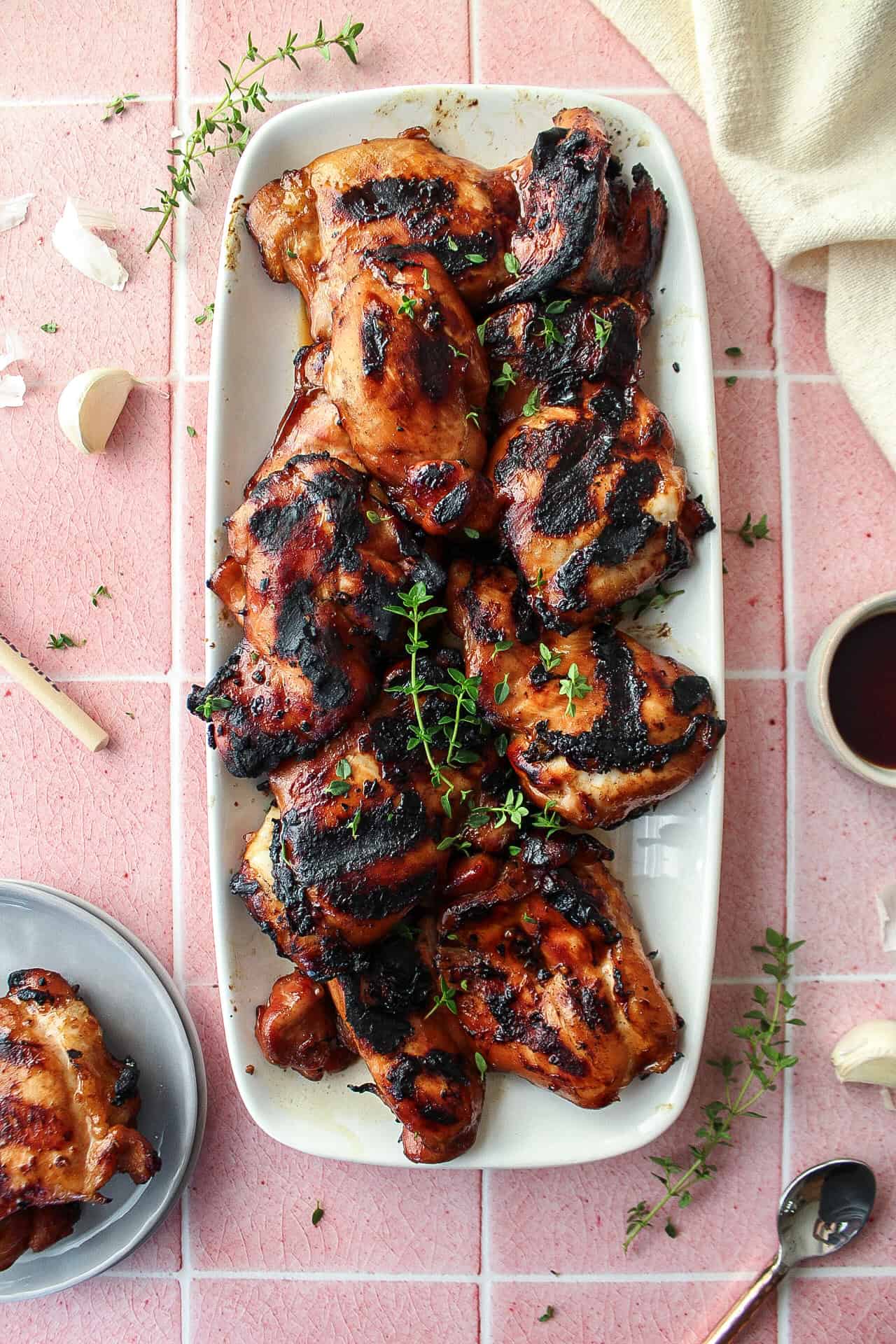 Grilled teriyaki chicken thigh on a plate topped with thyme.