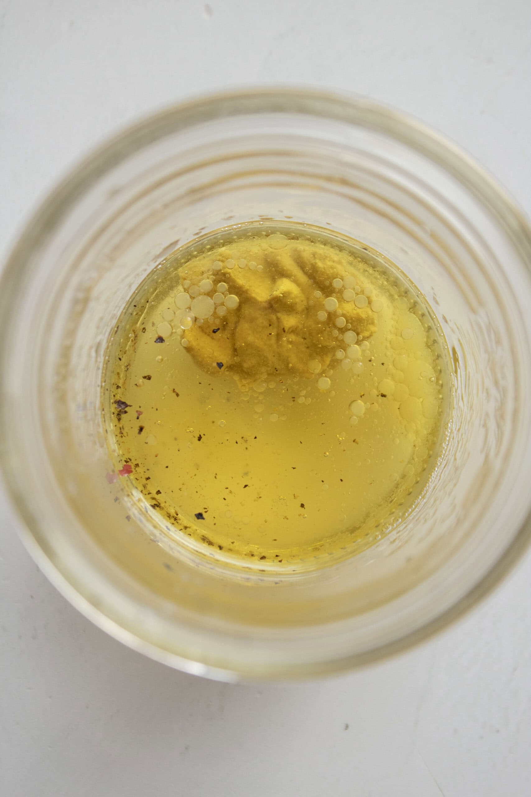 A mason jar with olive oil, white wine vinegar, salt, pepper, lemon juice, and dijon mustard to make a vinaigrette.